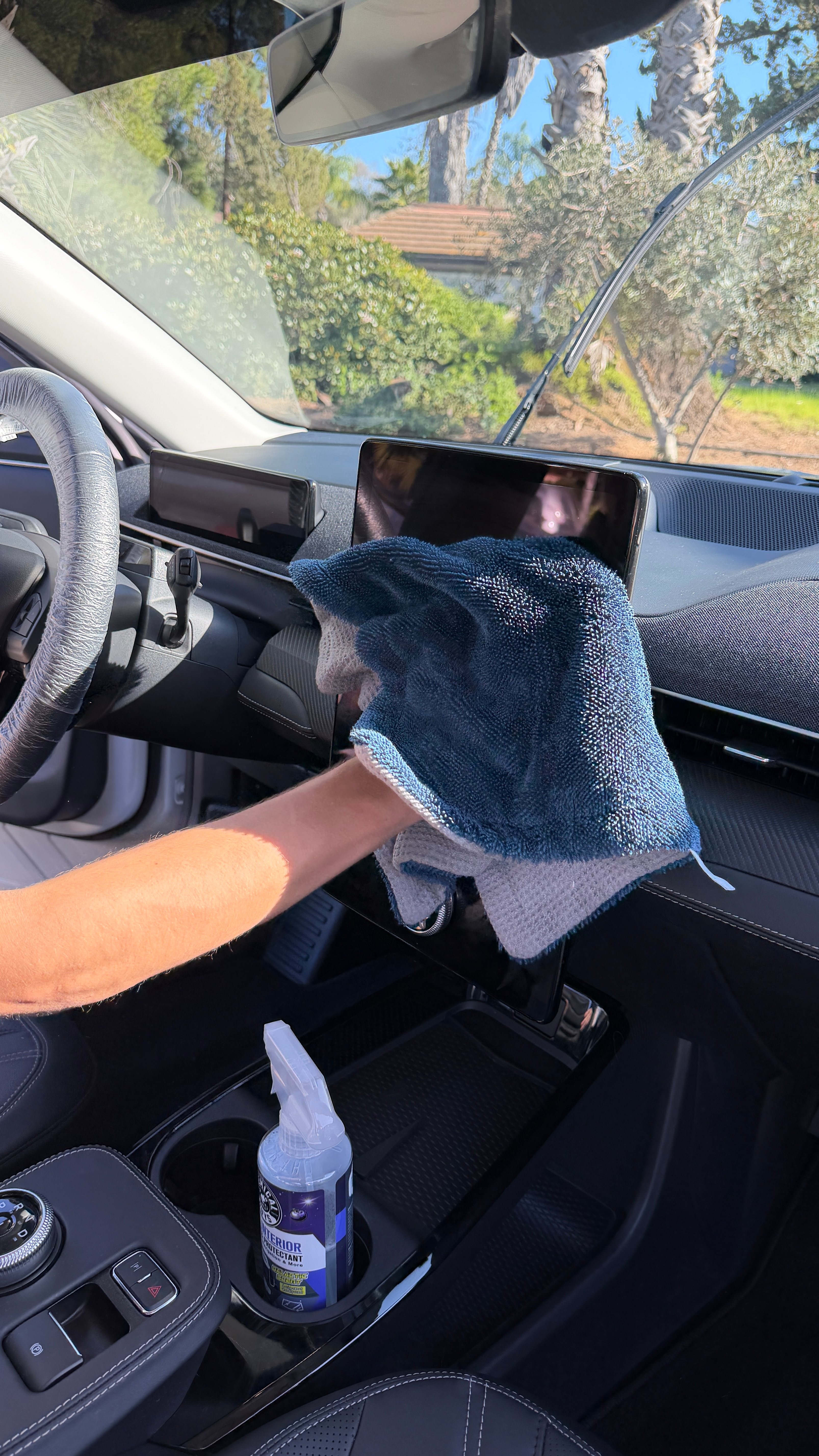 Wiping touchscreen with microfiber cloth during interior detail